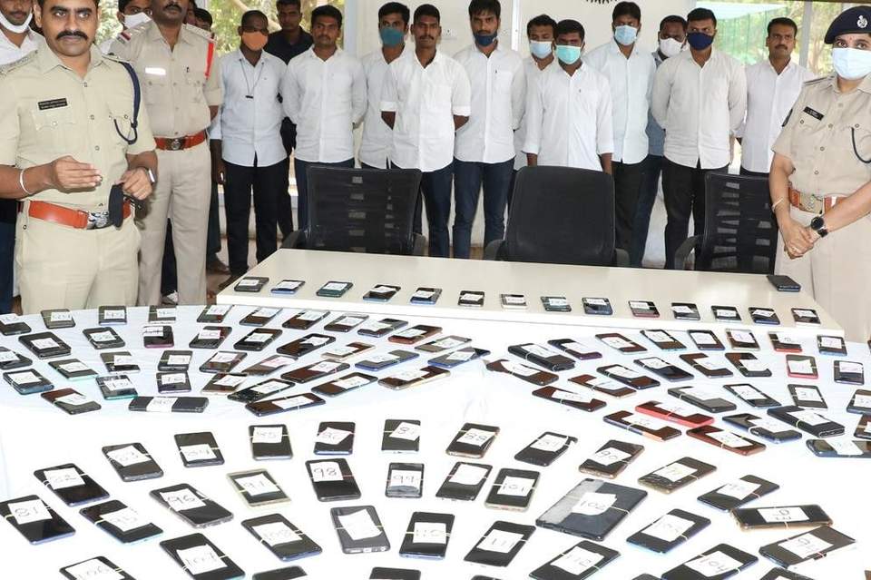 Police officers with a large number of recovered mobile phones laid out on tables